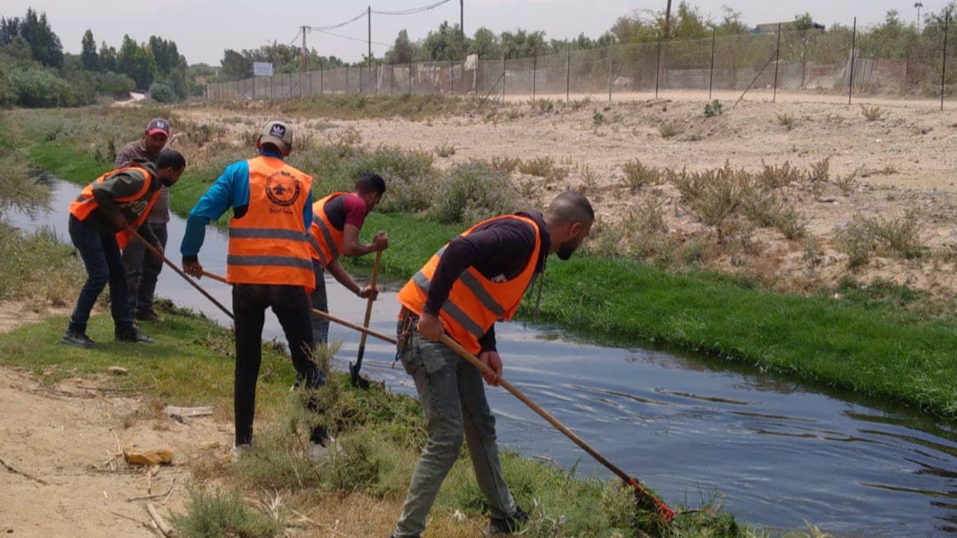 قسم الصحة والبيئة في بلدية البريج خلال أعمال إزالة الأعشاب على حواف مجرى وادي غزة،